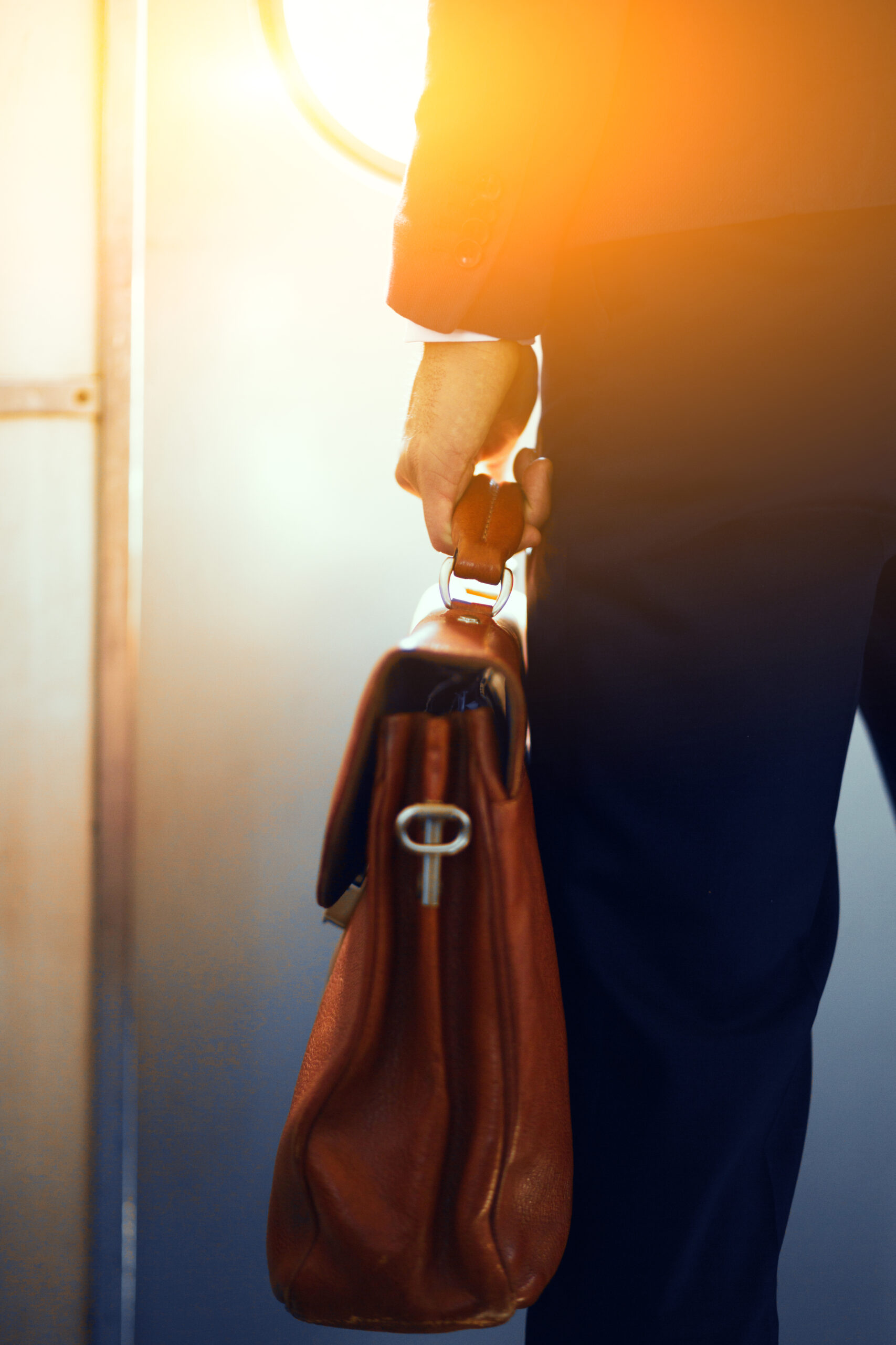 Man holding leather bag while on train.